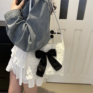 Detail of star embossed texture and black bow decoration on white tote bag for women