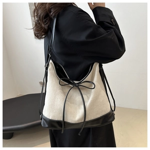 Detail view of canvas and leather patchwork tote bag showing refined bow knot design