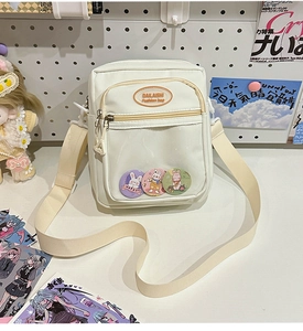 Close-up of beige nylon crossbody bag featuring a transparent front window with badges