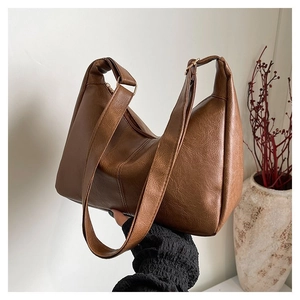 Detailaufnahme der braunen PU-Ledertasche mit breitem Gurt und goldener Metallschnalle