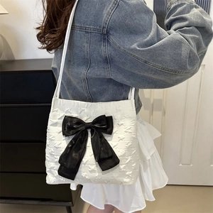 Close-up of white embossed tote bag featuring a large black bow detail on the side