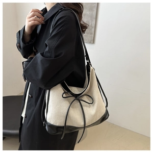 Detail of canvas tote bag with black leather trim and bow knot decoration on shoulder