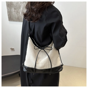 Hobo style canvas tote bag featuring contrast leather trim and a chic black bow detail