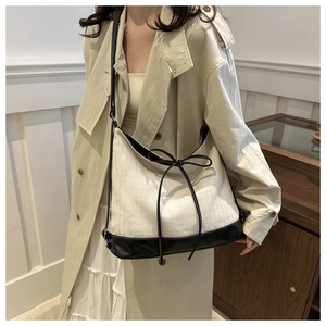 Detail of canvas tote bag with black leather trim and bow knot on a model