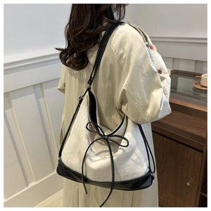 Canvas tote bag with black leather trim and bow detail shown on a female model