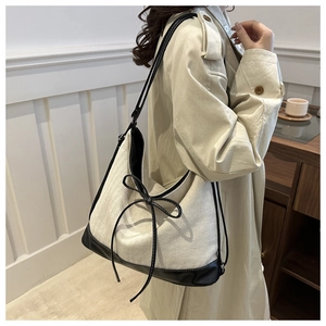 Detail of hobo bag with contrast leather bow, adjustable strap and textured canvas fabric