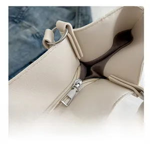 Détail de la fermeture éclair en argent sur un sac fourre-tout en cuir PU crème