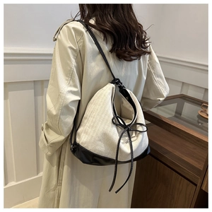 Detail view of canvas patchwork backpack with leather straps on a model wearing a trench coat