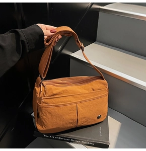 Gros plan du sac bandoulière en nylon orange avec fermetures éclair et sangle réglable