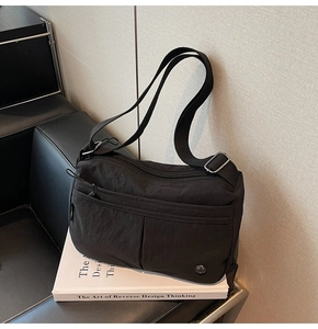 Détail du sac bandoulière en nylon noir avec poches multiples et compartiments zippés stylés