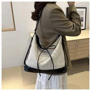 Detail showing contrast cream canvas and black leather shoulder bag with bow drawstring