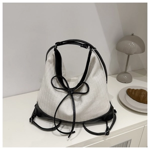 Detail of canvas tote bag with black leather handles and elegant bow knot design