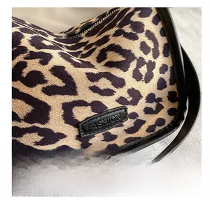 Close-up of leopard print fabric texture with black leather trim and metal zipper detail
