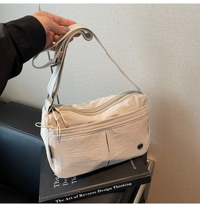 Vue détaillée du sac bandoulière beige en nylon avec poches multiples et sangle large