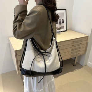 Minimalist canvas hobo bag with black leather accents and a bow for daily commuting