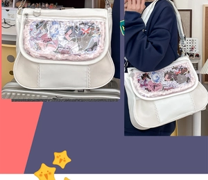 Detailed view of a white Ita bag with clear window featuring anime pins and badges