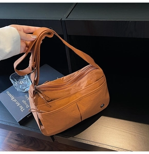 Détail d'un sac bandoulière en nylon caramel avec plusieurs poches zippées et sangle large