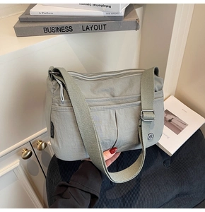 Détail d'un sac bandoulière en nylon vert avec plusieurs compartiments zippés