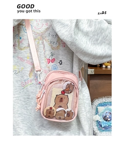Detail of pink ita bag featuring a clear PVC window with four cute capybara badges