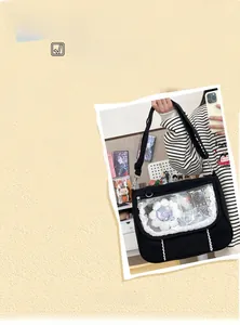 Detail of black ita bag with clear window and lace trim showing badges and plush toys