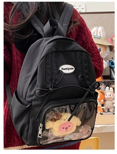 Detail of black ita bag featuring a clear front pocket with pink bear and bow decorations