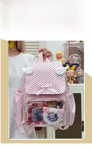 Detail of pink polka dot ita bag featuring transparent window and white plush wings