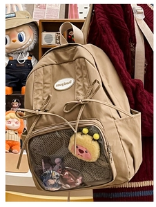 Detail of khaki ita bag with bow ribbons, transparent display layer, and plush charms