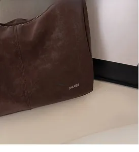 Détail du sac cabas vintage en cuir marron foncé avec texture premium et logo argenté