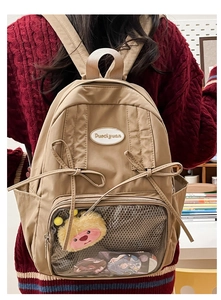 Close-up of beige nylon Ita bag with transparent display window and bow detail