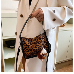 Detail of leopard print faux fur handbag with black leather trim and plush charm accessory