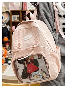 Close-up of pink ita bag with clear window, bow details, and pins in a cozy lifestyle setting