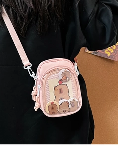 Detailed view of a pink Ita bag with clear window featuring cute capybara accessories