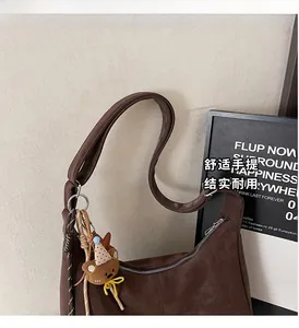 Détail du sac à bandoulière vintage marron avec breloque ours et fermeture éclair argent