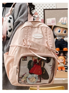 Detailed view of the pink ita bag featuring a large clear window with anime badges