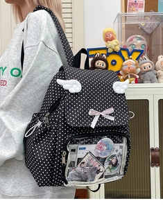 Detailed side view of cute black polka dot ita bag with plush wings and clear window