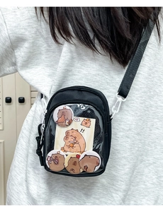 Detail of black ita bag with transparent window showing Kapibara badges and charms