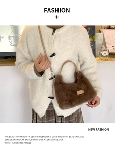 Detailed close-up of brown faux fur hobo bag featuring a metallic logo plaque and leather handle