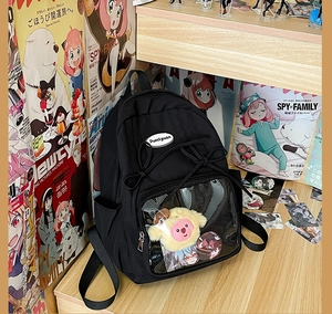 Close-up of black Ita Bag transparent window featuring anime badges and plush accessories
