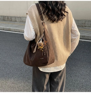 Détail du sac hobo en daim marron avec pendentif ours et logo de marque sur le côté