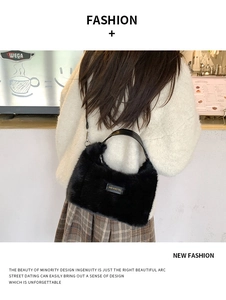 Detail of plush black shoulder bag featuring a love every day label and leather handle
