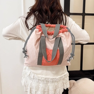 Pink drawstring backpack showing light nylon fabric and orange pocket detail on a model