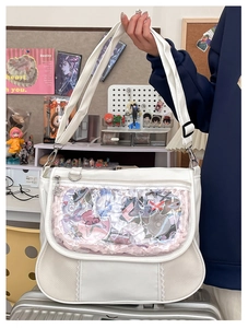 Detailed close-up of white Ita bag with clear window and adjustable shoulder strap