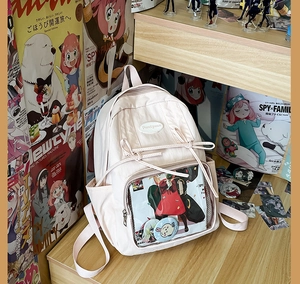 Detail shot of pink ita bag with transparent window showing anime badges and bow