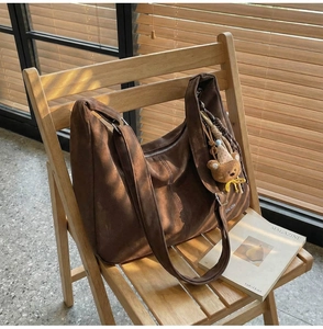 Vue détaillée d'un grand sac hobo en daim marron avec pendentif ours sous le soleil