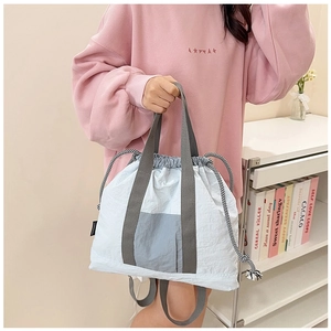 Detail of light blue nylon tote bag with drawstring closure and contrasting grey panels