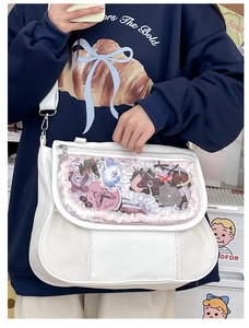 Detail of white PU ita bag with clear window showing anime badges and butterfly charms