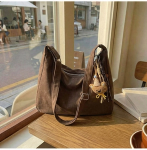 Détail d'un sac cabas vintage marron avec texture suédée et un charmant ours en peluche