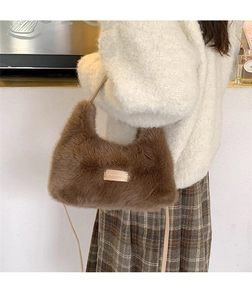 Detailed close-up of brown faux fur hobo bag with gold metal plate and beige strap