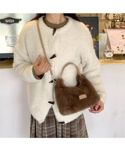 Detailed close-up of dark brown plush faux fur bag with leather strap in a cafe setting