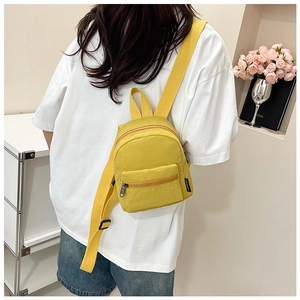 Close-up of bright yellow nylon mini backpack with adjustable straps worn by a model